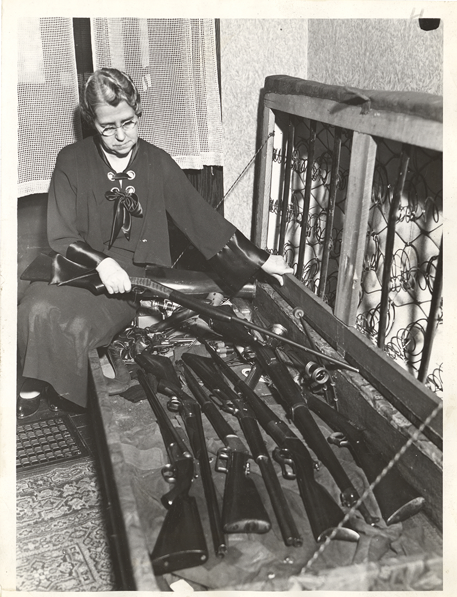 Unidentified woman with guns hidden under box frame mattress, c. 1930. | Heinz History Center