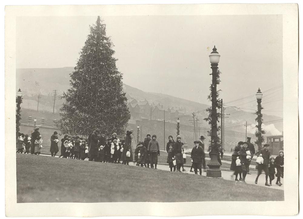 The children of employees at the Edgar Thompson Works file past a giant Christmas tree holding their annual “holiday treat.” | Heinz History Center