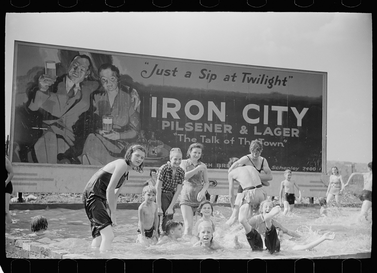 Local children enjoy a dip in the pool in front of an Iron City billboard, July 1938. Photo by Arthur Rothstein, courtesy of the Library of Congress.