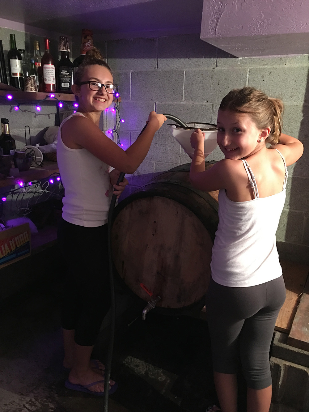 Two members of the Mancini family help siphon grape juice into a barrel for aging. Courtesy of the Mancini family.