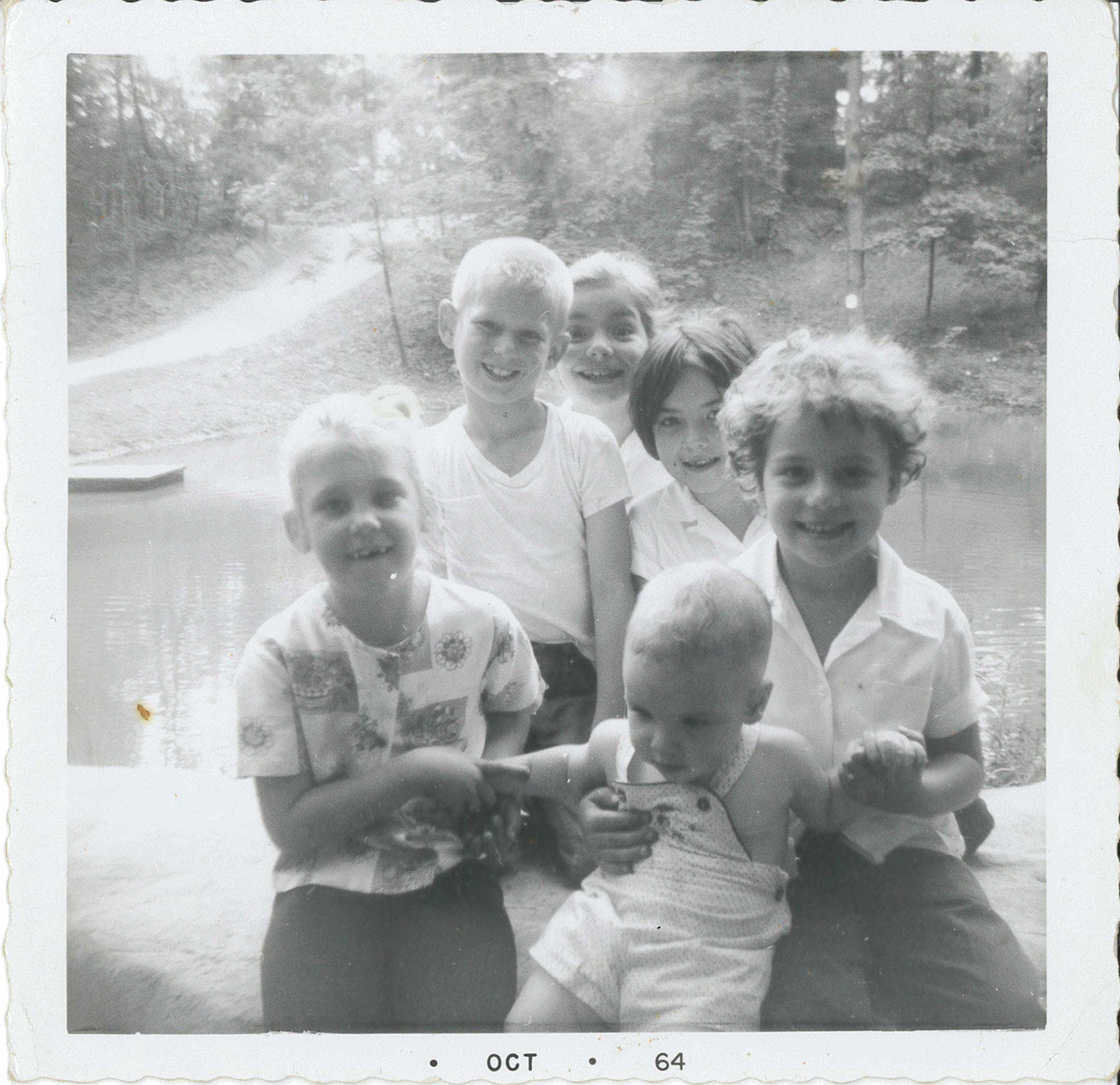 From the back of the photograph: “Taken the last day of school June – 64. Terri and Barry Andrews. Patience, Francie, Erin(?) and Danny at the Pond on Miller Property later Meadowcroft Village.” The blacksmith shop, still there today, would be finished that July on the hill directly across the pond.