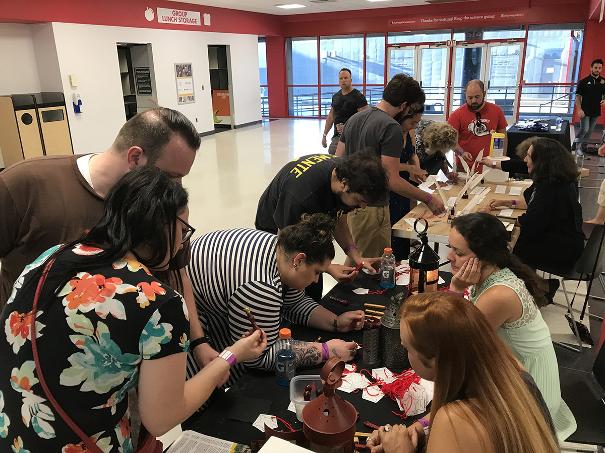 Branwyn (foreground) helps guests at the Science Center’s 21+ Night Block Party. Branwyn represented the Fort Pitt Museum and helped guests make wax seals.