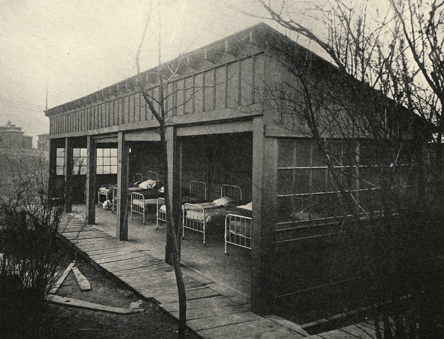 Open-air shacks with beds for patients, c. 1920.