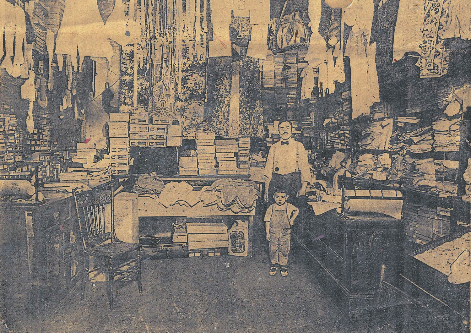 Sam Reznik and his son Milton Reznik, better known as “Motty,” standing inside Sam Reznik & Sons dry goods store on Logan Street. Like many dry goods businesses of the day, the store displayed its entire inventory. “They thought if people didn’t see everything they had, they wouldn’t know that they had it,” his granddaughter Rochelle Blumenfeld recalled. “So nothing was hidden.” Courtesy of Rochelle Blumenfeld. Sam Reznik and his son Milton Reznik, better known as “Motty,” standing inside Sam Reznik & Sons dry goods store on Logan Street. Like many dry goods businesses of the day, the store displayed its entire inventory. “They thought if people didn’t see everything they had, they wouldn’t know that they had it,” his granddaughter Rochelle Blumenfeld recalled. “So nothing was hidden.” Courtesy of Rochelle Blumenfeld.