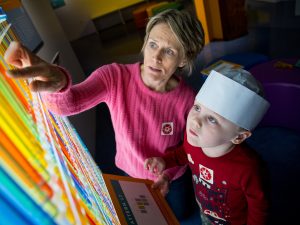 A caregiver and a child explore a colorful exhibit at the Heinz History Center.