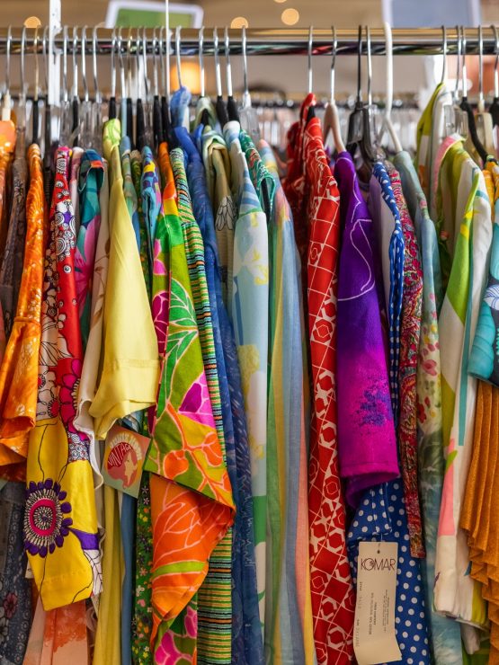 A clothing rack displays assorted colorful, patterned shirts and dresses on hangers, reflecting vintage Pittsburgh fashion styles. *AI generated alt text