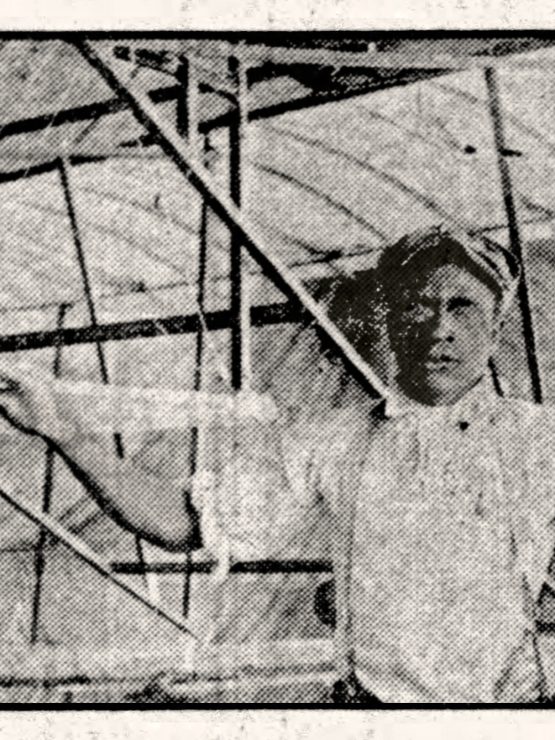 Black and white image of a young man in a cap and light shirt, resting his hand on an early aircraft or glider's wooden frame. *AI generated alt text