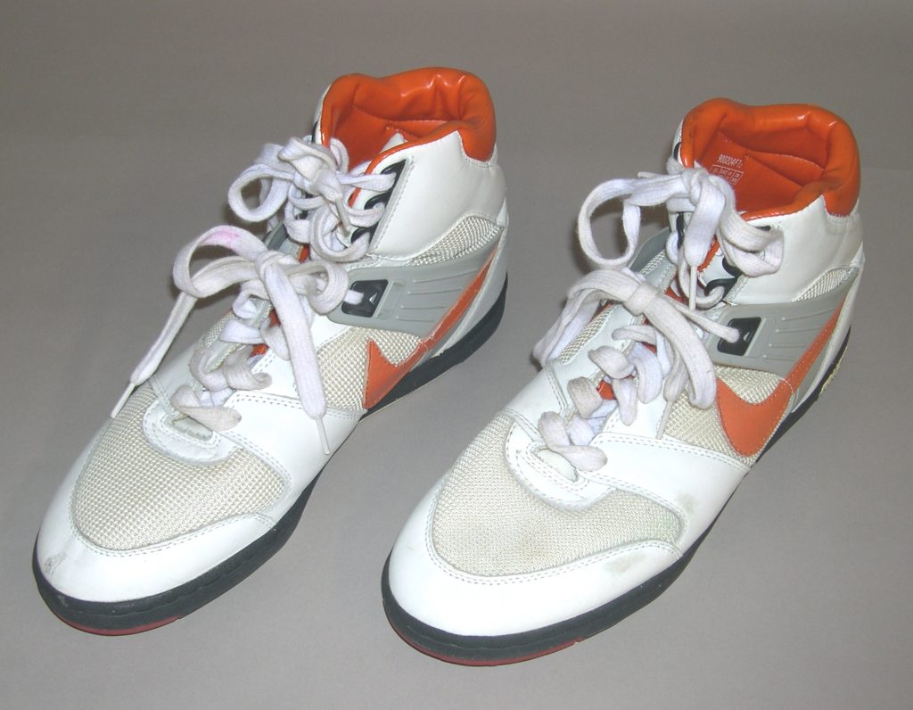 A pair of high-top sneakers with white mesh and leather, orange interiors, orange Nike swooshes, gray accents, and white laces. *AI generated alt text