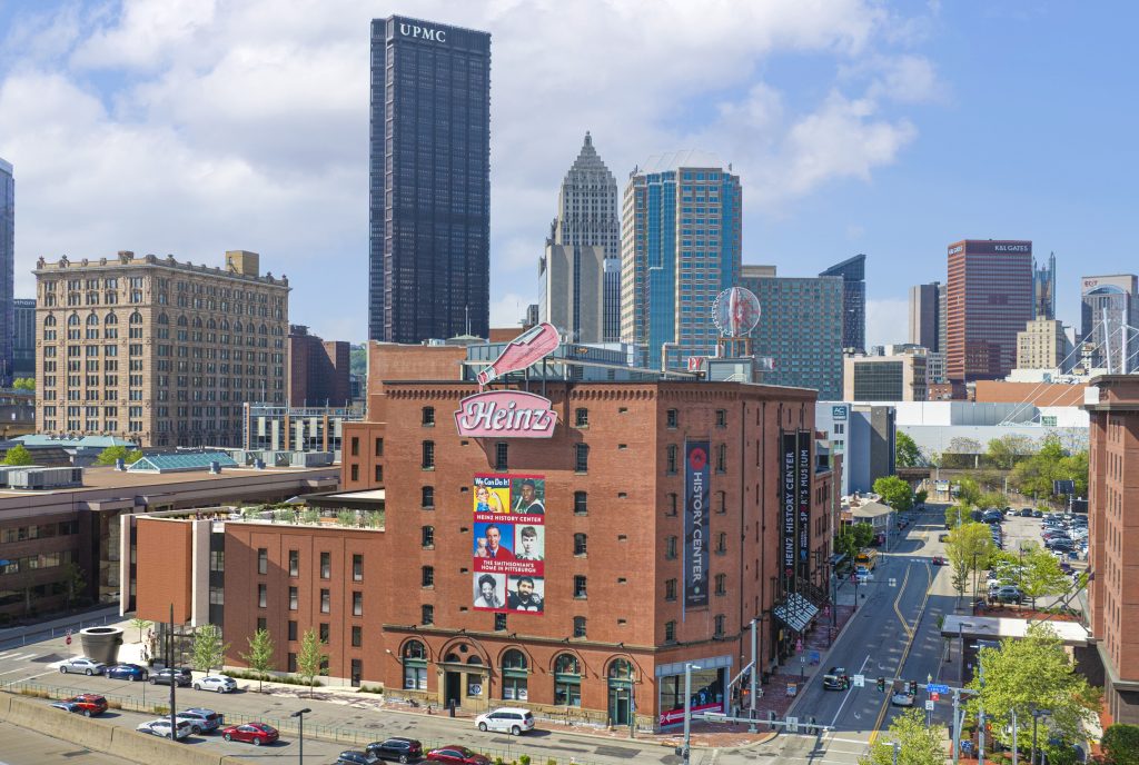 Downtown Atlanta skyline with tall buildings, red-brick structure with murals, Hard Rock Cafe sign, and cars on city streets below. *AI generated alt text