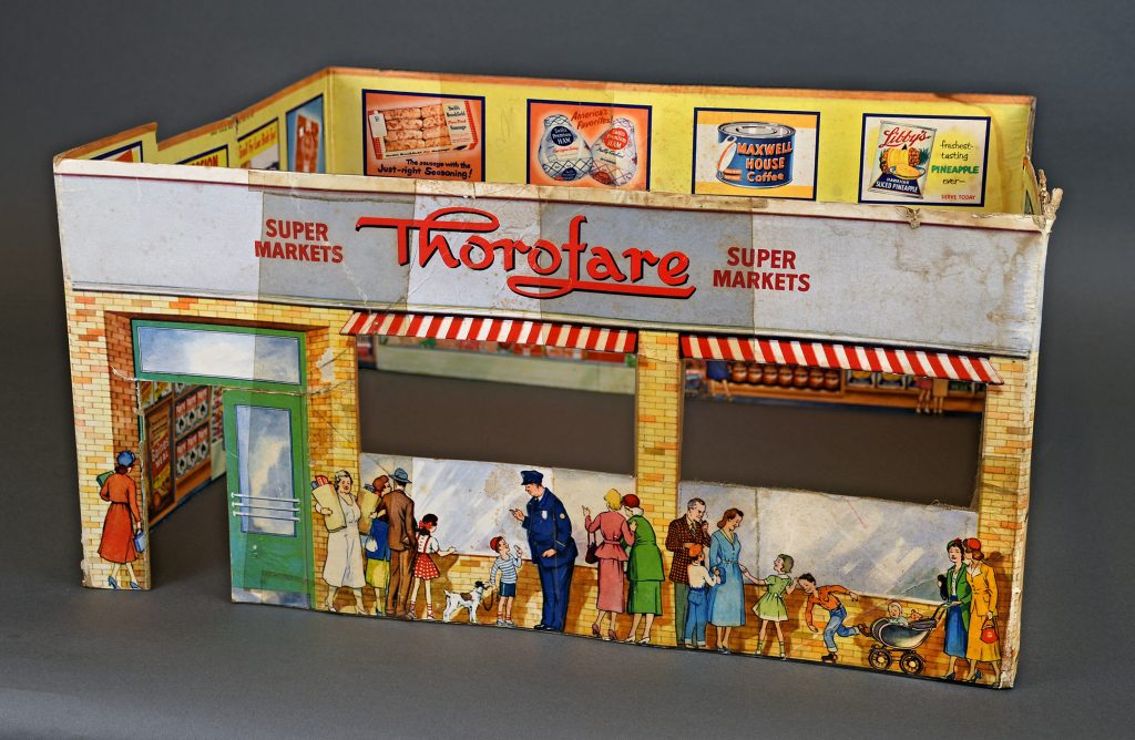 Vintage cardboard model of a Thorofare Super Market with illustrated shoppers, groceries, ads, and striped awnings over windows. *AI generated alt text