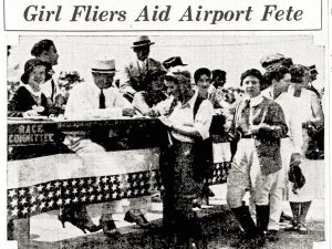 Black-and-white photograph showing women pilots in aviation uniforms seated at a decorated table with a Race Committee sign, interacting with men and women during an airport event. The scene takes place indoors, and a newspaper headline above them reads: Girl Fliers Aid Airport Fete. *AI generated alt text
