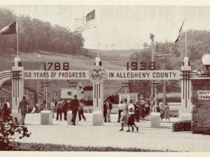 Black-and-white photograph showing a group of people gathered at the entrance to a park. An archway above the entrance displays the dates “1788 - 1938” and the phrase “150 Years of Progress in Allegheny County.” Flags are positioned around the archway, and a sign reads “South Park.” Trees and hills can be seen in the background. *AI generated alt text