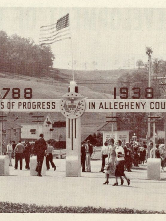 Black-and-white photograph showing a group of people gathered at the entrance to a park. An archway above the entrance displays the dates “1788 - 1938” and the phrase “150 Years of Progress in Allegheny County.” Flags are positioned around the archway, and a sign reads “South Park.” Trees and hills can be seen in the background. *AI generated alt text